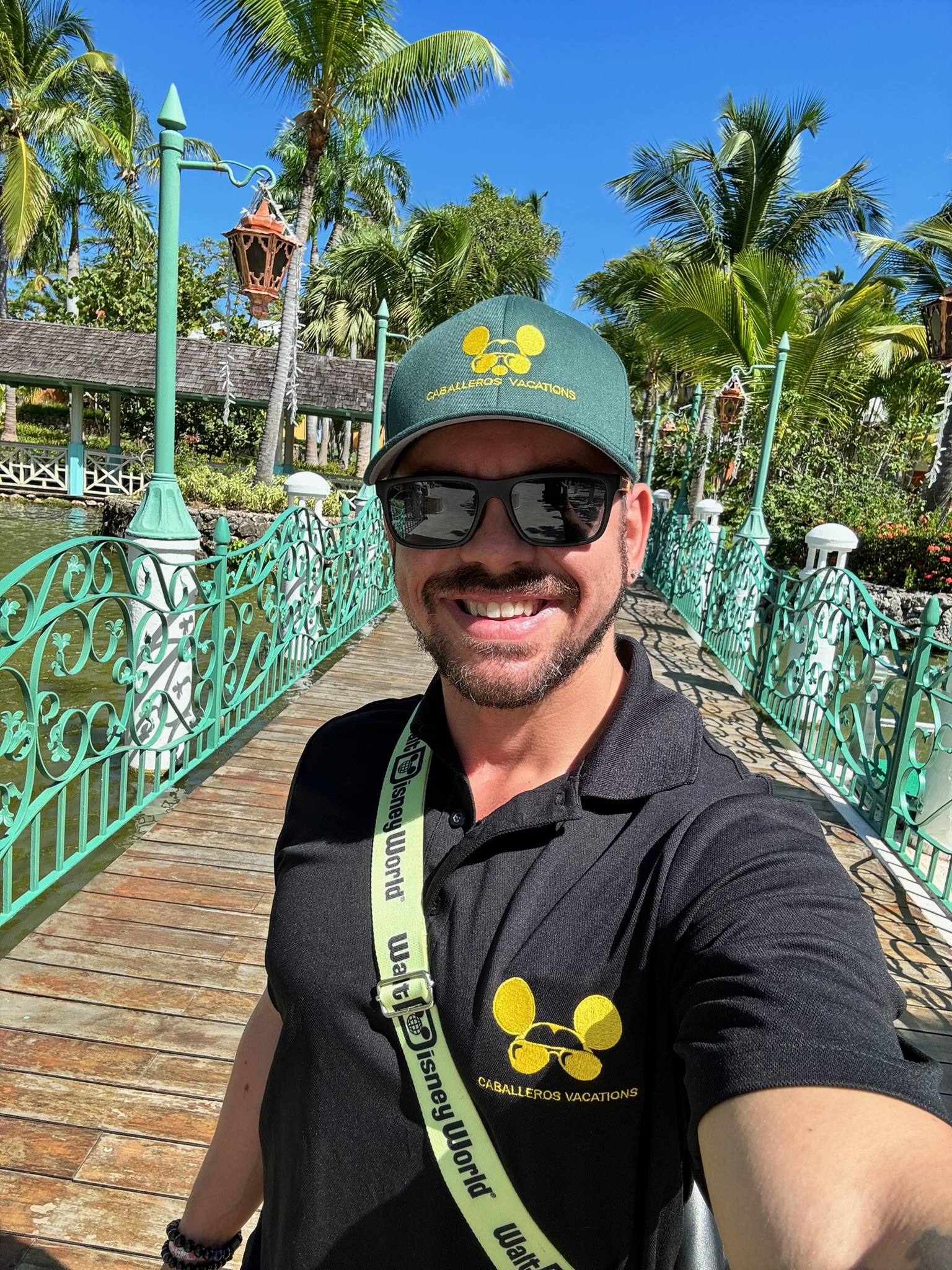 Mike Boguslavskiy at a tropical resort in the Caballeros Vacations polo with a Walt Disney World lanyard